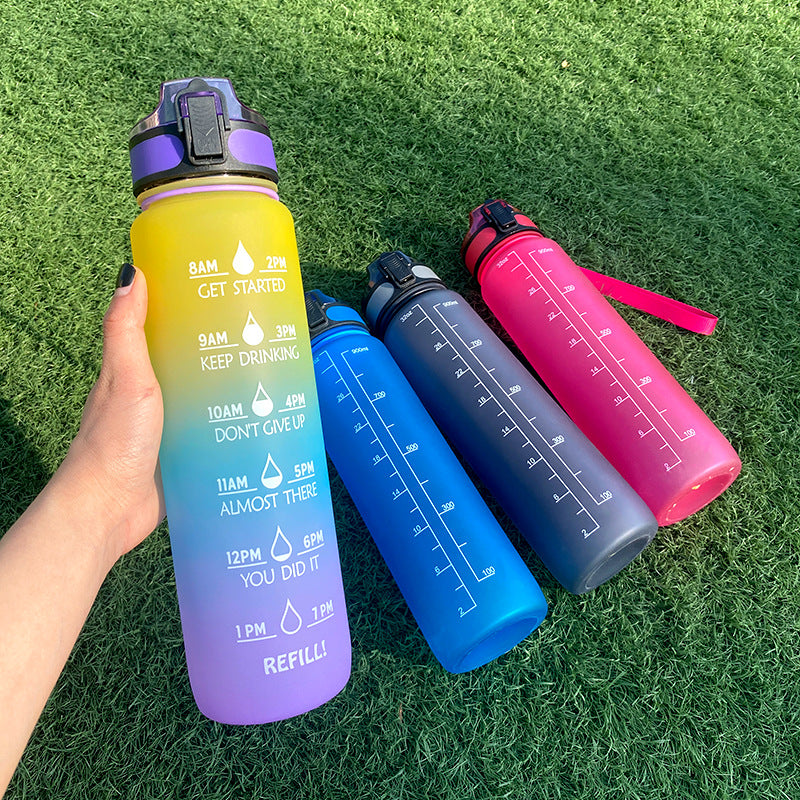 Four colorful water bottles with motivational time markers on a grass background