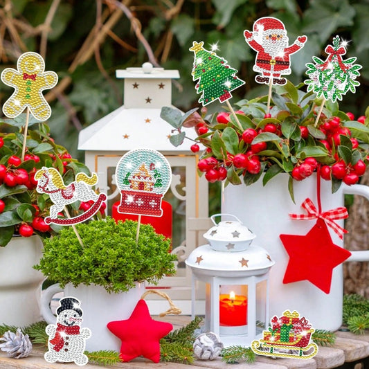 Finished Christmas diamond-art stakes arranged among festive greenery