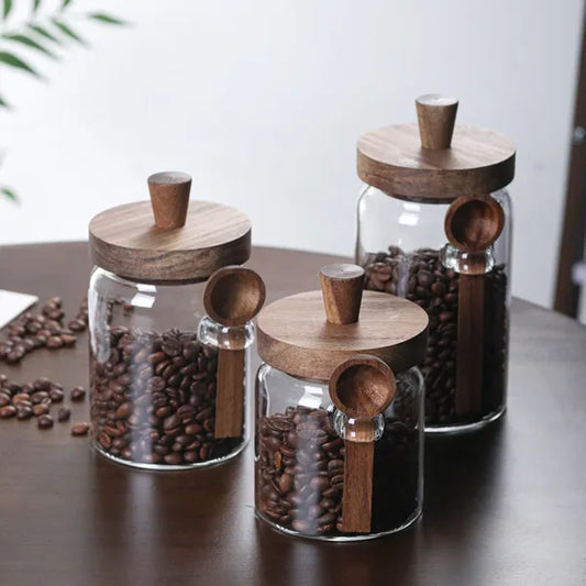 Three glass storage jars with lids and side-mounted spoons